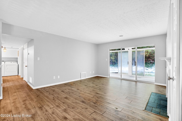 unfurnished room with washer and dryer, a textured ceiling, and light hardwood / wood-style flooring