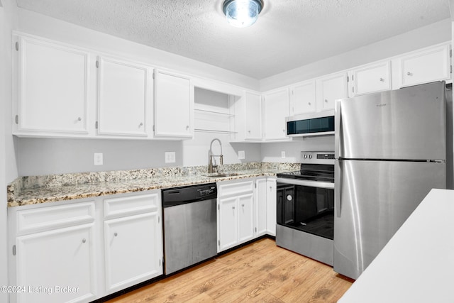 kitchen with light hardwood / wood-style floors, white cabinetry, sink, and appliances with stainless steel finishes