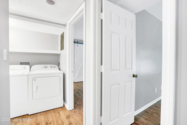 clothes washing area featuring washing machine and clothes dryer, light hardwood / wood-style flooring, and a textured ceiling