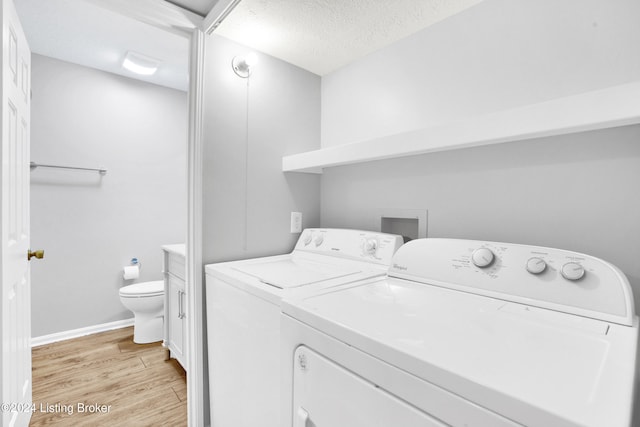 laundry area with light hardwood / wood-style floors, washing machine and dryer, and a textured ceiling