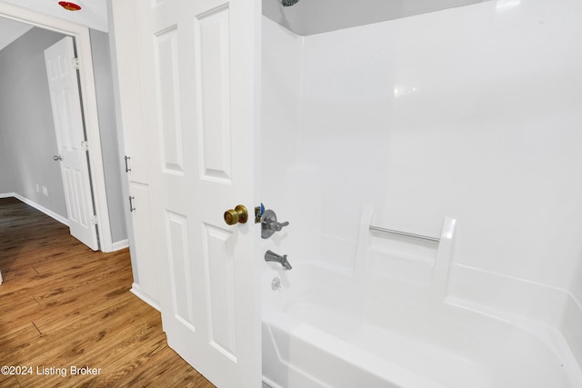 bathroom with hardwood / wood-style flooring and washtub / shower combination