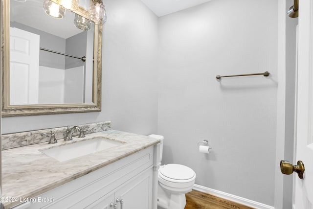 bathroom with walk in shower, hardwood / wood-style floors, vanity, and toilet