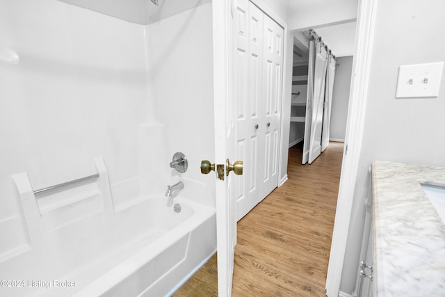 bathroom featuring vanity, wood-type flooring, and washtub / shower combination