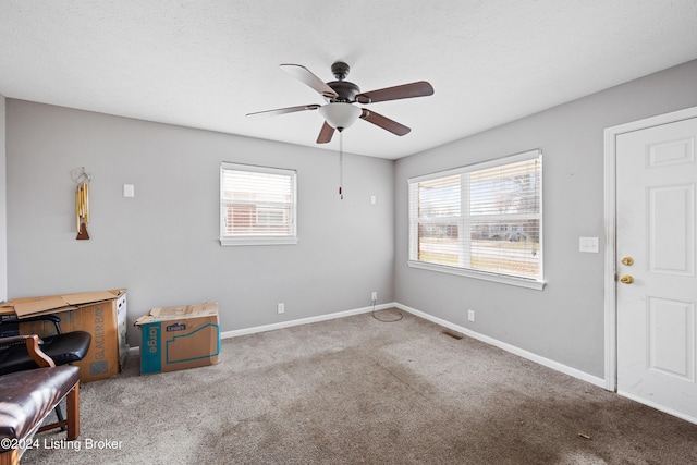 interior space with ceiling fan, light colored carpet, and a textured ceiling