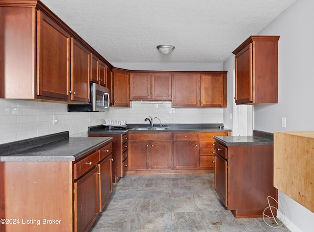 kitchen with backsplash, sink, and a textured ceiling