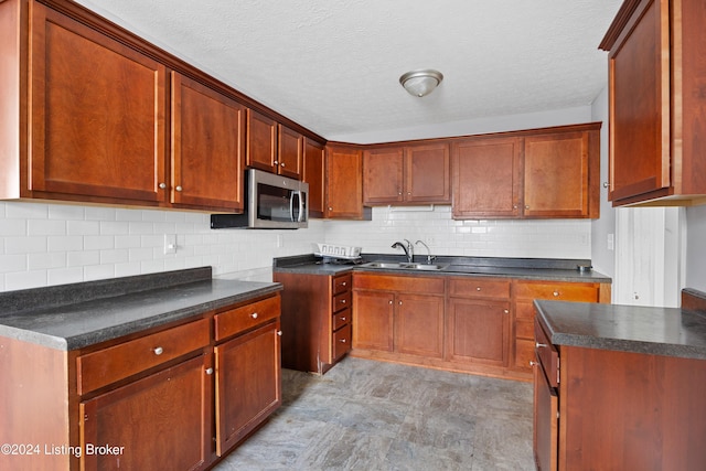 kitchen with a textured ceiling, tasteful backsplash, and sink