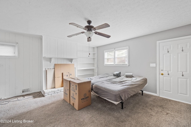 bedroom featuring ceiling fan, light colored carpet, and a textured ceiling