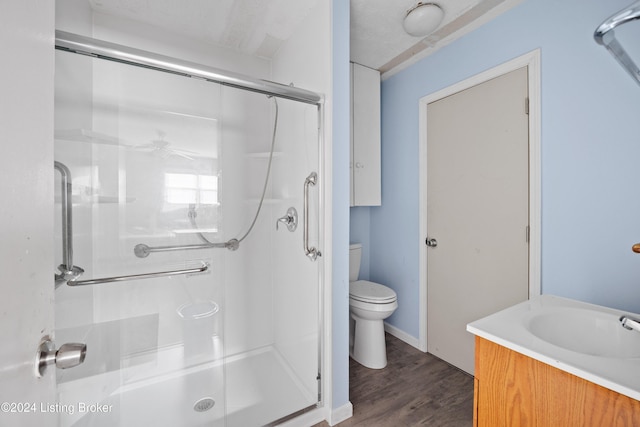 bathroom featuring walk in shower, vanity, ceiling fan, wood-type flooring, and toilet