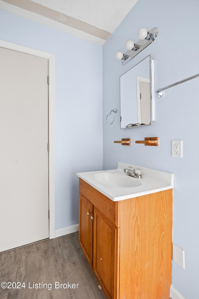 bathroom with hardwood / wood-style floors, vanity, and a textured ceiling