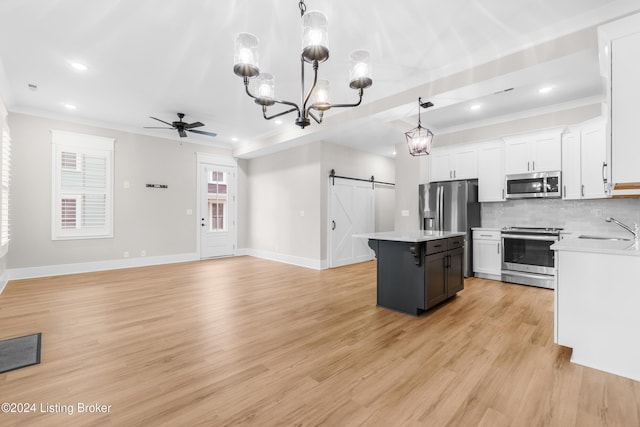 kitchen with a center island, white cabinets, hanging light fixtures, a barn door, and appliances with stainless steel finishes