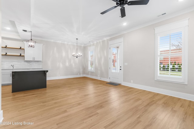 unfurnished living room with plenty of natural light, ceiling fan with notable chandelier, and light hardwood / wood-style flooring