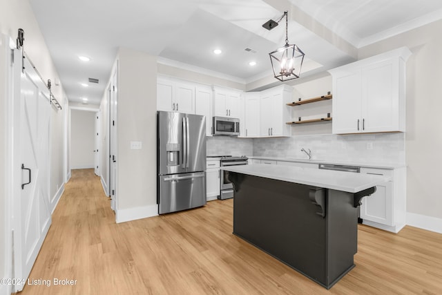 kitchen featuring white cabinets, a barn door, stainless steel appliances, and light hardwood / wood-style flooring