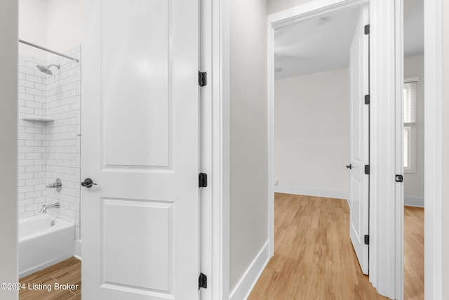 bathroom with hardwood / wood-style flooring and tiled shower / bath