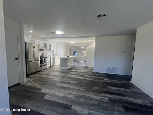 kitchen featuring backsplash, white cabinets, dark wood-type flooring, and appliances with stainless steel finishes