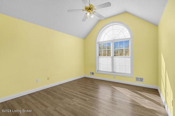 empty room with a textured ceiling, hardwood / wood-style flooring, ceiling fan, and lofted ceiling