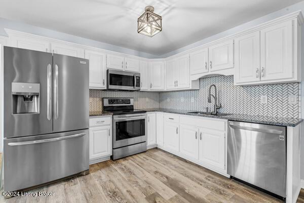 kitchen featuring decorative backsplash, appliances with stainless steel finishes, sink, light hardwood / wood-style flooring, and white cabinetry