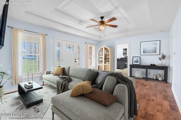 living room featuring a raised ceiling, ceiling fan, and hardwood / wood-style flooring