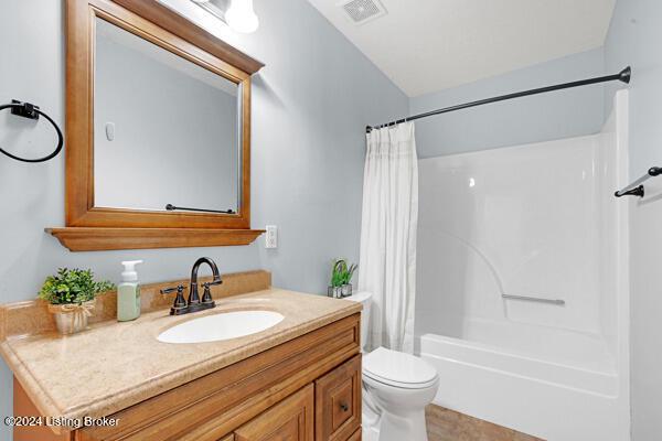 full bathroom with vanity, shower / bath combination with curtain, and toilet