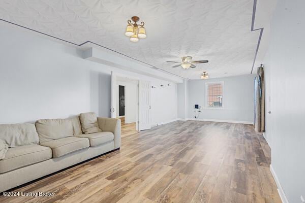 unfurnished living room with hardwood / wood-style floors, ceiling fan, and a textured ceiling