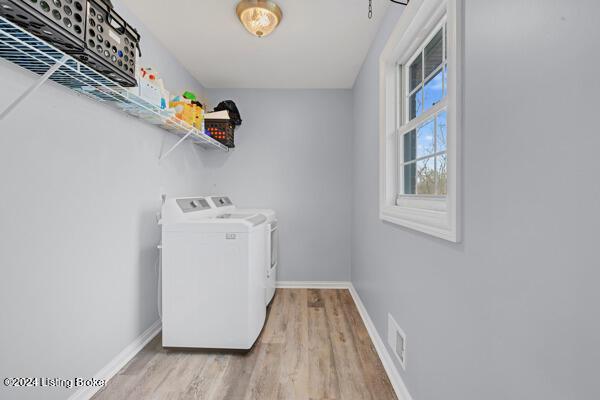 laundry area featuring separate washer and dryer and light hardwood / wood-style flooring