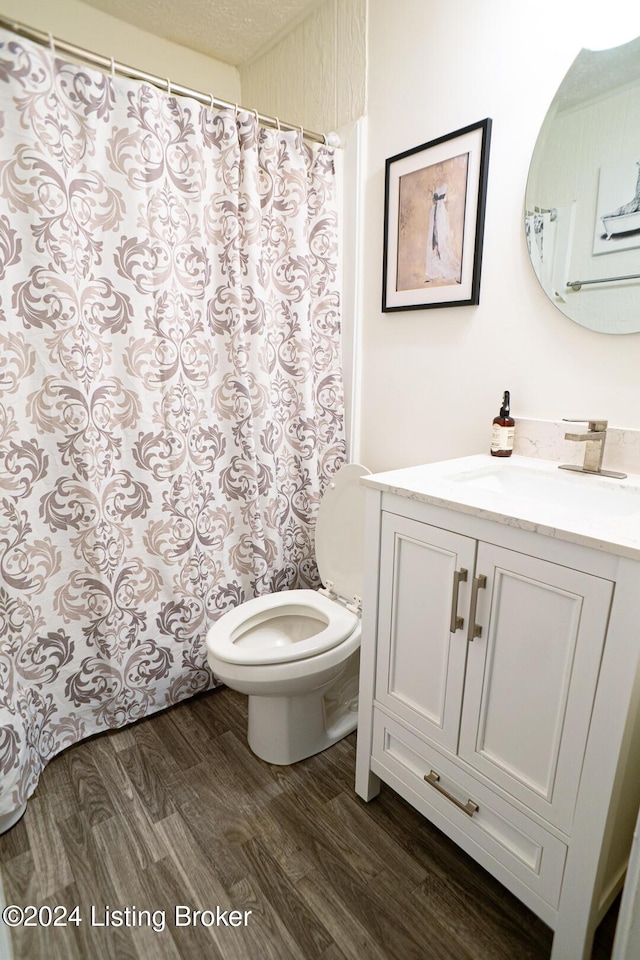 bathroom with hardwood / wood-style floors, vanity, toilet, and a textured ceiling