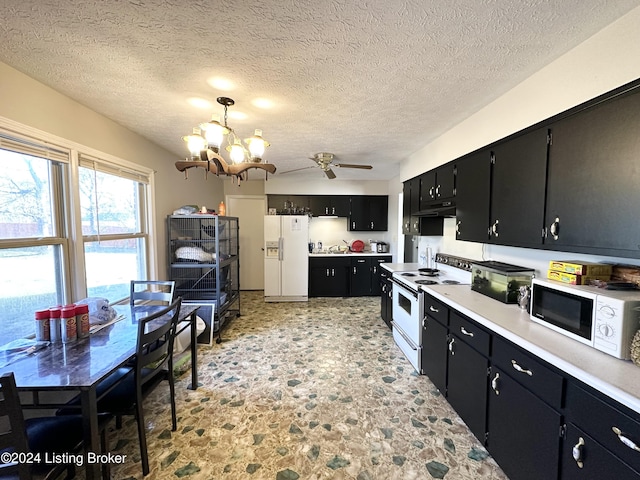 kitchen featuring ceiling fan with notable chandelier, white appliances, a textured ceiling, and decorative light fixtures