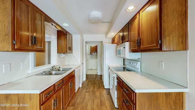 kitchen featuring light wood-type flooring, sink, and white appliances