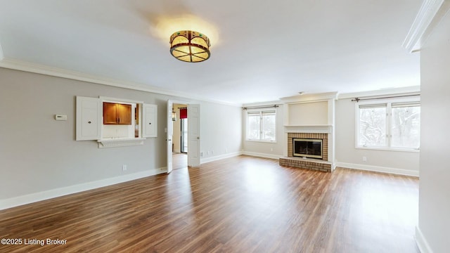 unfurnished living room featuring a brick fireplace, ornamental molding, and hardwood / wood-style floors