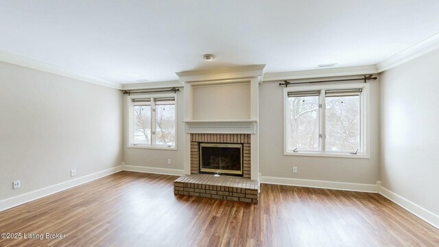 unfurnished living room with a brick fireplace, crown molding, and hardwood / wood-style flooring