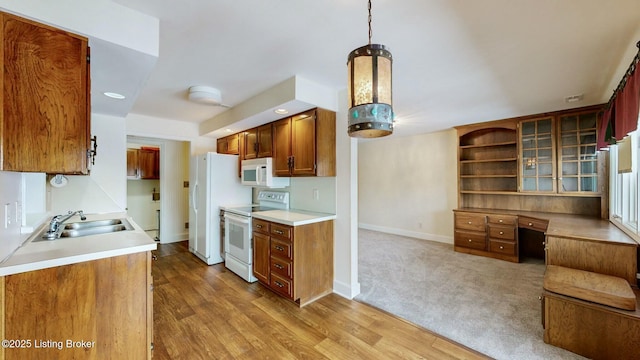 kitchen featuring hanging light fixtures, sink, white appliances, and hardwood / wood-style floors