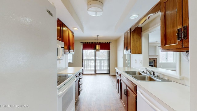 kitchen featuring light hardwood / wood-style floors, sink, white appliances, and hanging light fixtures