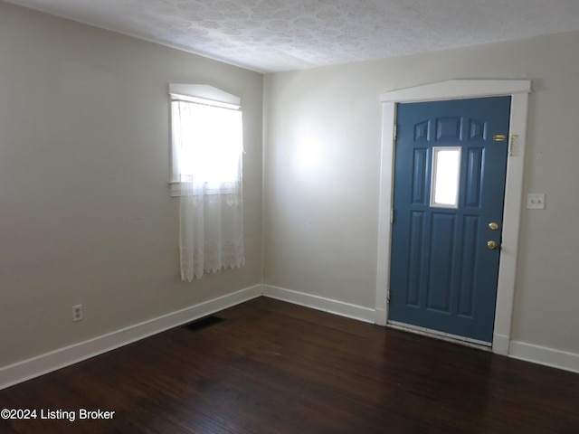 foyer entrance with a textured ceiling and dark hardwood / wood-style floors