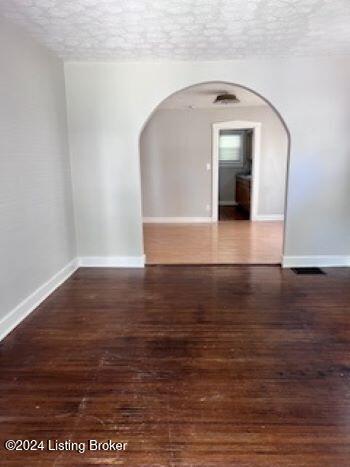 empty room with a textured ceiling and dark wood-type flooring