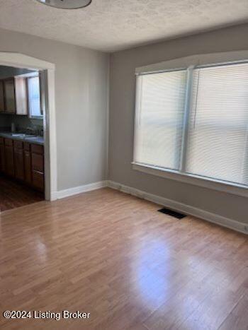 unfurnished dining area with light hardwood / wood-style floors and a textured ceiling