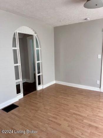 unfurnished room with hardwood / wood-style floors and a textured ceiling