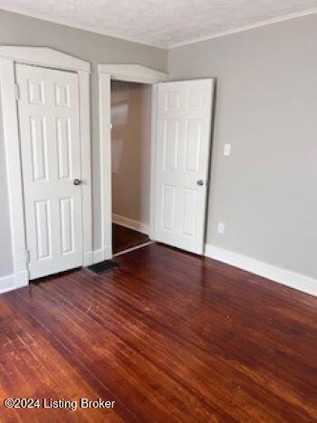 unfurnished bedroom with a textured ceiling, dark hardwood / wood-style floors, and a closet