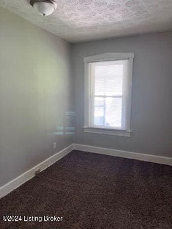 carpeted empty room with a textured ceiling