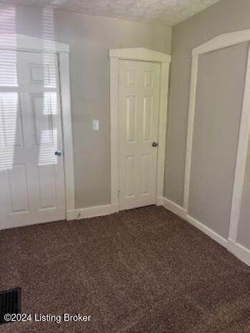 interior space with a textured ceiling and dark carpet