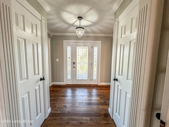 entryway featuring a textured ceiling, a notable chandelier, ornamental molding, and dark wood-type flooring