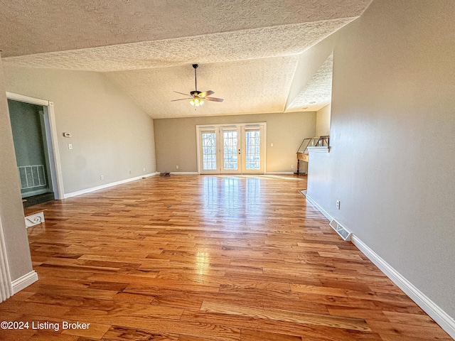 unfurnished living room featuring vaulted ceiling, ceiling fan, a textured ceiling, and light wood-type flooring