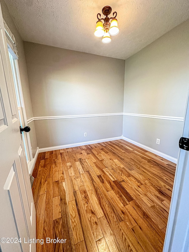 unfurnished room featuring wood-type flooring and a textured ceiling