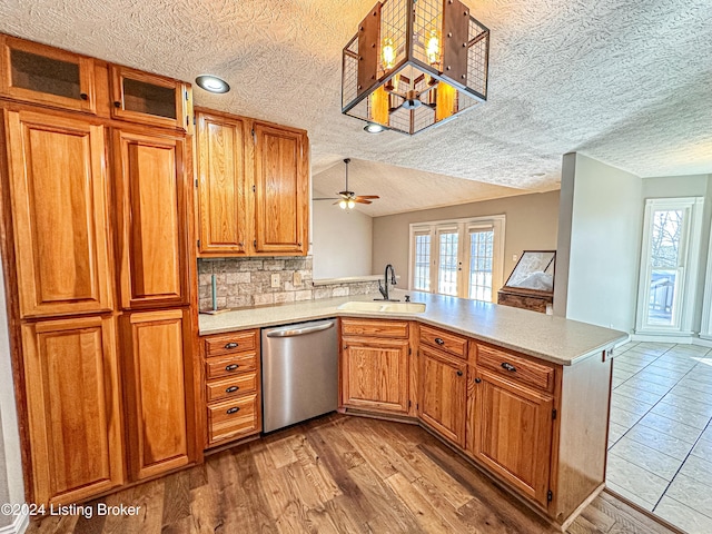 kitchen featuring kitchen peninsula, light wood-type flooring, ceiling fan, sink, and dishwasher