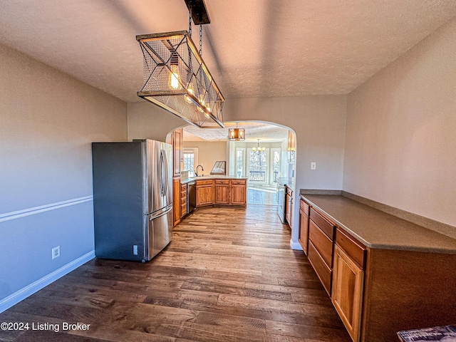 kitchen featuring kitchen peninsula, stainless steel appliances, hanging light fixtures, and hardwood / wood-style flooring