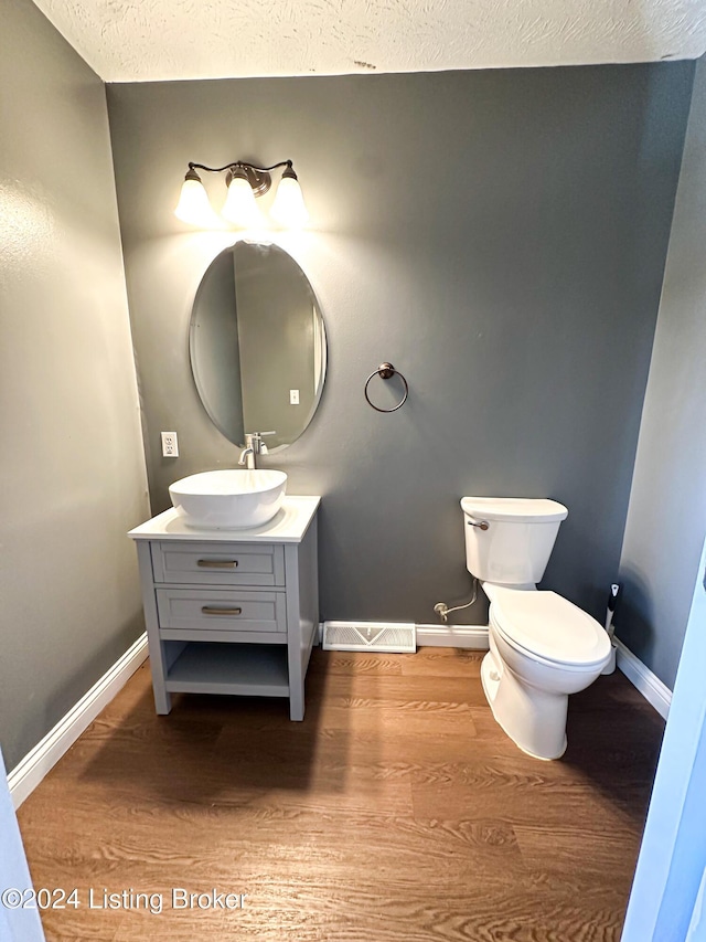 bathroom with vanity, toilet, wood-type flooring, and a textured ceiling