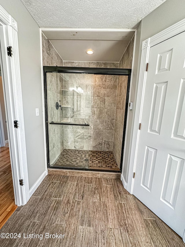 bathroom featuring a shower with shower door and a textured ceiling