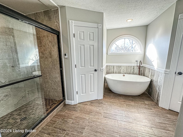 bathroom featuring a textured ceiling, independent shower and bath, and wood walls