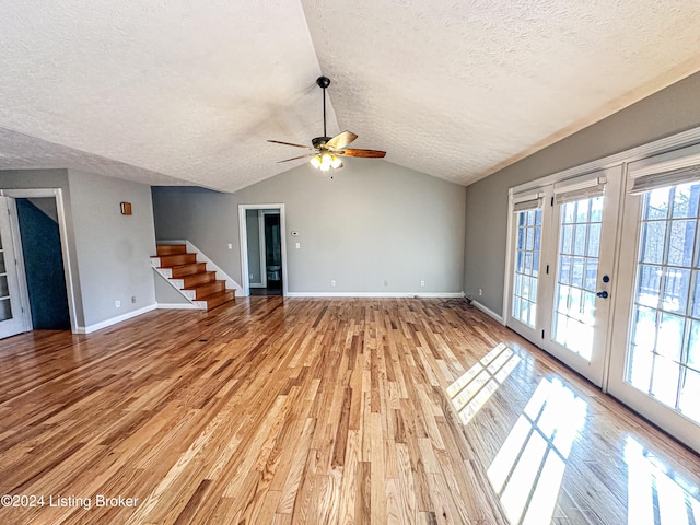 unfurnished living room featuring french doors, vaulted ceiling, light hardwood / wood-style flooring, ceiling fan, and a textured ceiling