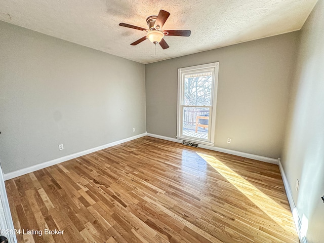 unfurnished room featuring ceiling fan, light wood-type flooring, and a textured ceiling