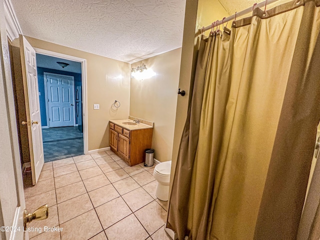 bathroom featuring tile patterned flooring, vanity, a textured ceiling, and toilet