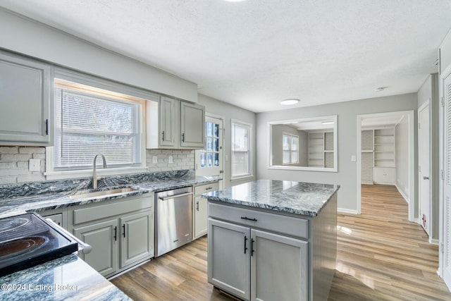 kitchen featuring stainless steel dishwasher, a center island, gray cabinetry, and light wood-type flooring